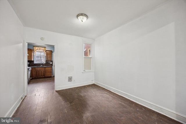 spare room with dark wood-style flooring, baseboards, and a sink