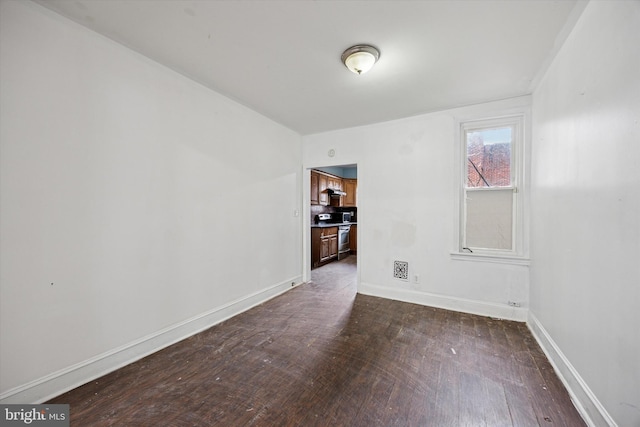 spare room with baseboards and dark wood finished floors