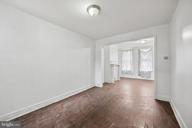 spare room featuring dark wood-type flooring and baseboards