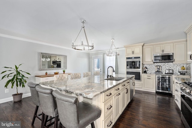 kitchen with beverage cooler, a sink, cream cabinets, dark wood finished floors, and appliances with stainless steel finishes