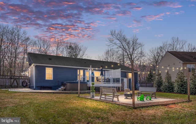 back of property featuring an outdoor fire pit, a patio area, a lawn, and a hot tub