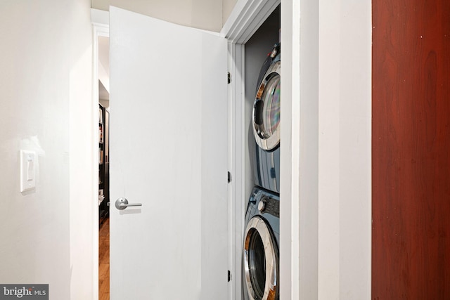 washroom featuring stacked washer and clothes dryer and laundry area