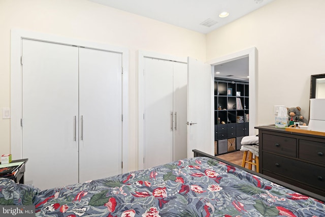 bedroom with visible vents, recessed lighting, multiple closets, and wood finished floors