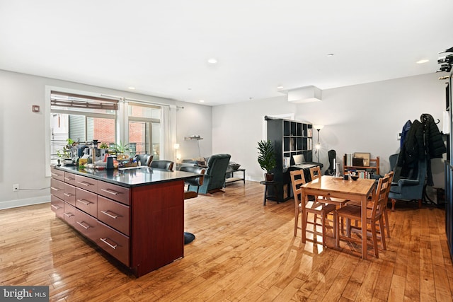 kitchen featuring dark countertops, a kitchen island, baseboards, and light wood-style floors