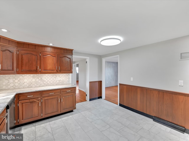 kitchen with visible vents, wood walls, wainscoting, brown cabinets, and stainless steel dishwasher