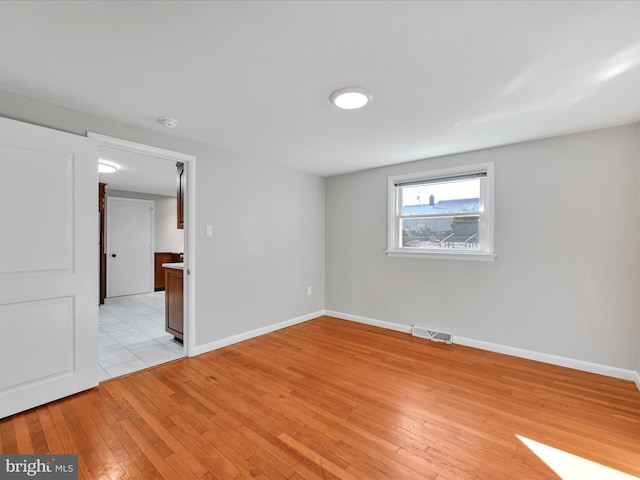 unfurnished room featuring visible vents, light wood-type flooring, and baseboards