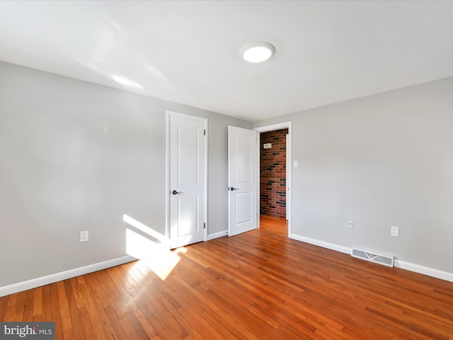 empty room with visible vents, baseboards, and hardwood / wood-style floors