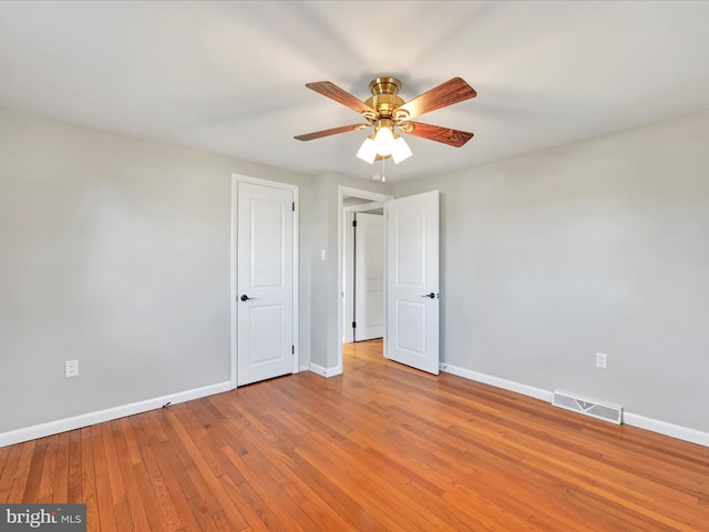 spare room with visible vents, ceiling fan, light wood-type flooring, and baseboards