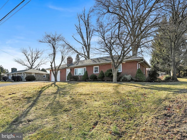 view of front of home with an attached carport, brick siding, a front yard, and a chimney