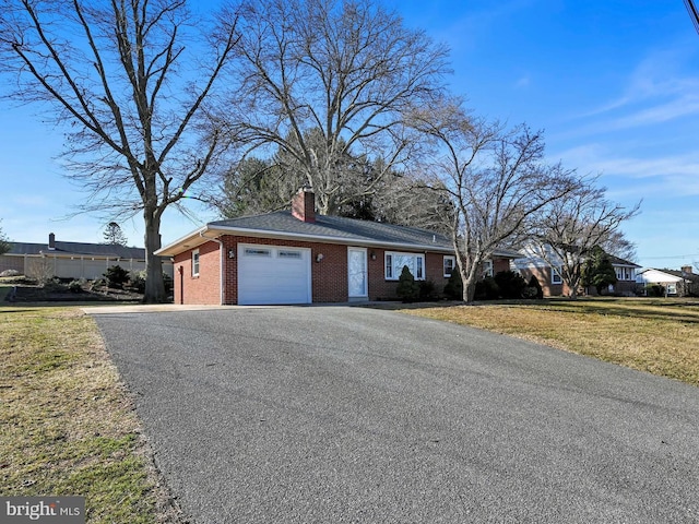 single story home with aphalt driveway, brick siding, a garage, and a front lawn