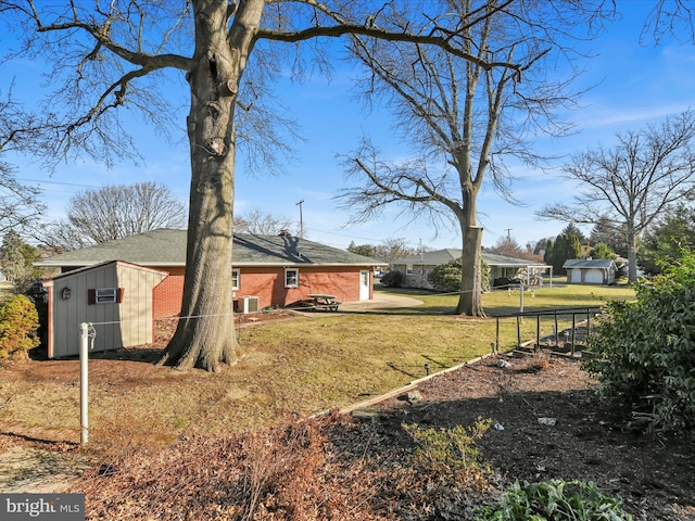 exterior space with an outdoor structure, a yard, brick siding, and a patio