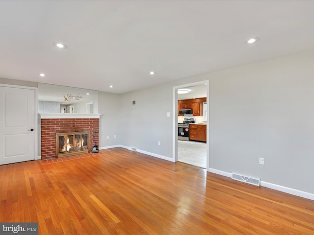 unfurnished living room with visible vents, baseboards, light wood-style floors, and a fireplace