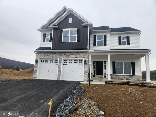 craftsman-style home with driveway, stone siding, a porch, board and batten siding, and a garage