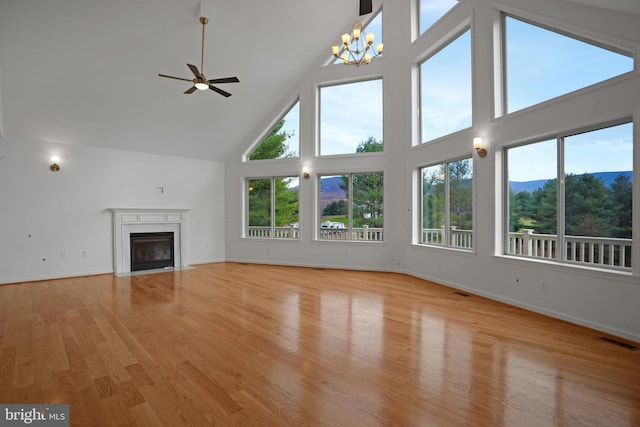 unfurnished living room featuring visible vents, a fireplace with flush hearth, high vaulted ceiling, light wood finished floors, and baseboards