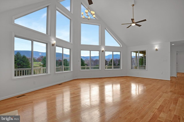 unfurnished living room featuring visible vents, a healthy amount of sunlight, a mountain view, and light wood-type flooring