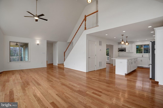 unfurnished living room with stairway, plenty of natural light, and light wood finished floors