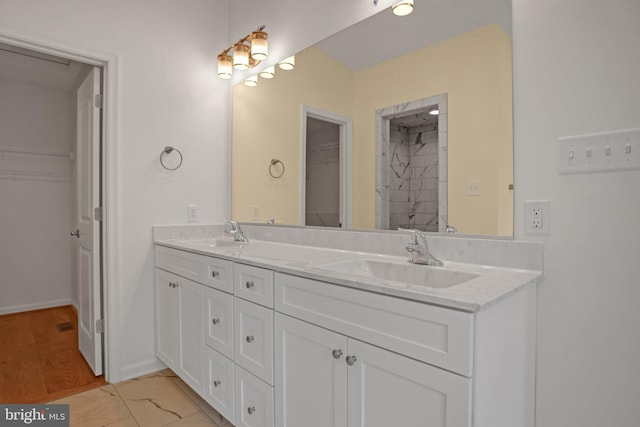 bathroom with a sink, a walk in closet, marble finish floor, and double vanity