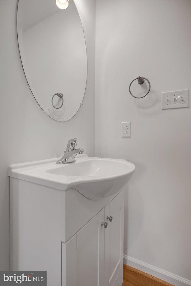 bathroom featuring baseboards, wood finished floors, and vanity