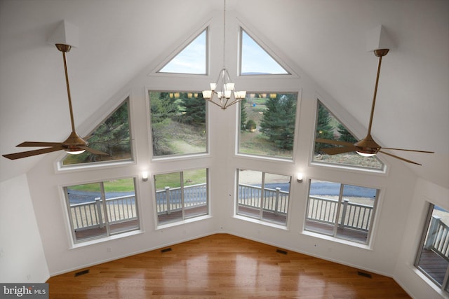 unfurnished living room featuring high vaulted ceiling, wood finished floors, and ceiling fan with notable chandelier