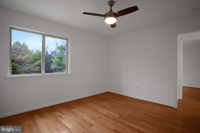 spare room featuring baseboards, ceiling fan, and light wood finished floors