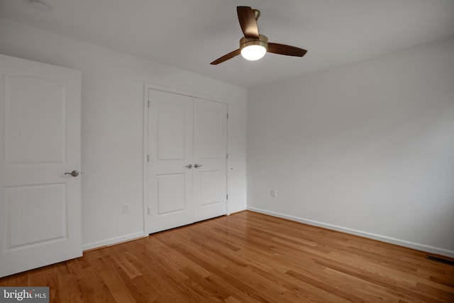 unfurnished bedroom featuring visible vents, baseboards, wood finished floors, a closet, and a ceiling fan