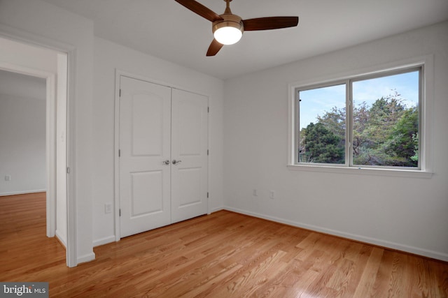 unfurnished bedroom featuring a closet, light wood-style flooring, a ceiling fan, and baseboards