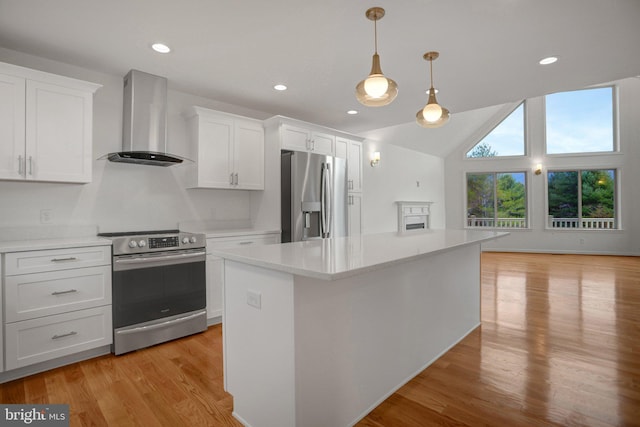 kitchen featuring light wood-style flooring, wall chimney range hood, white cabinetry, appliances with stainless steel finishes, and light countertops