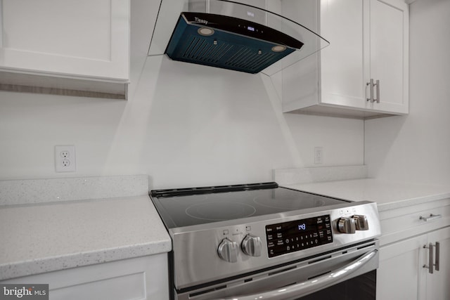 kitchen with light stone counters, stainless steel electric range, white cabinetry, and extractor fan