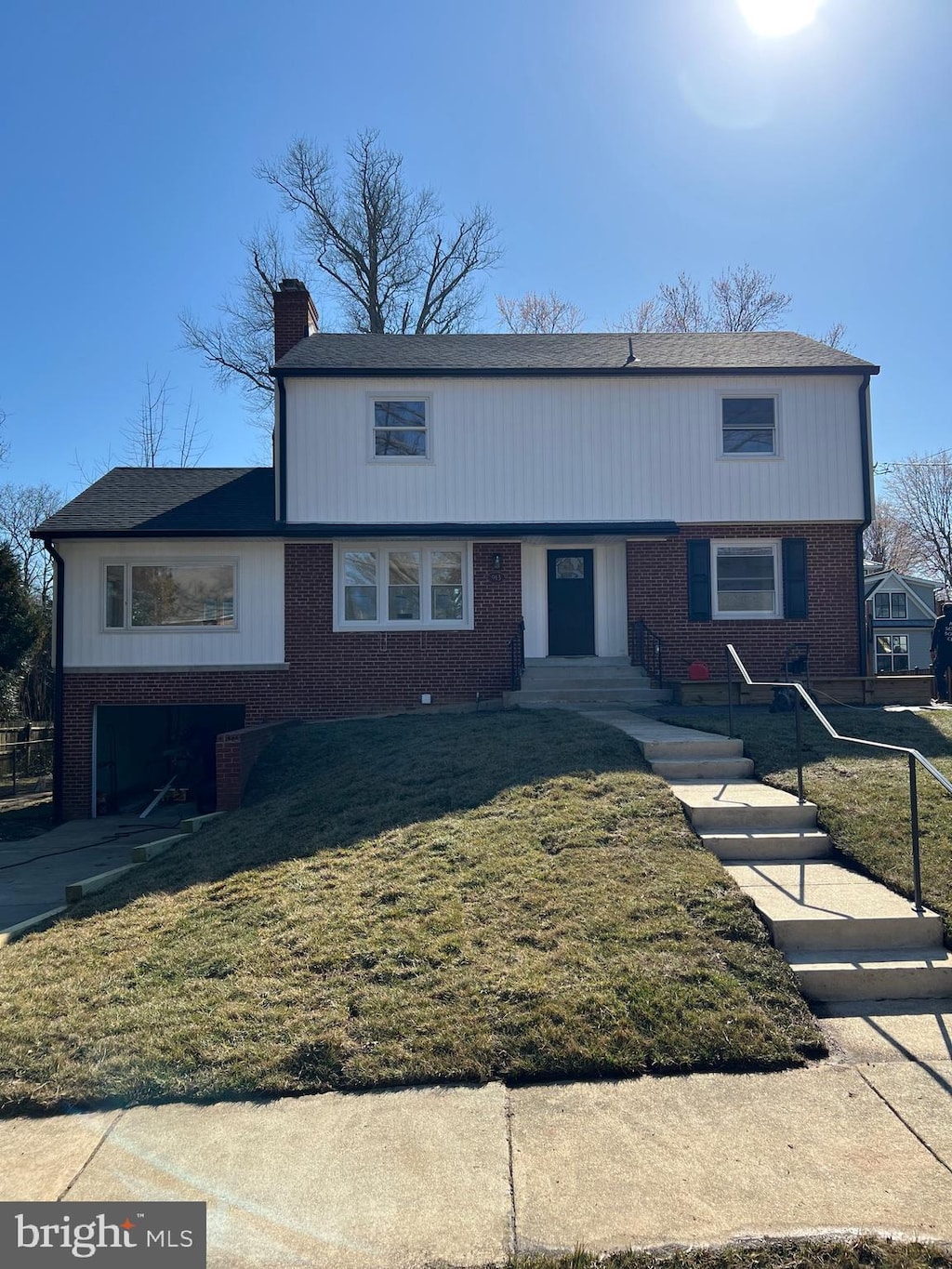 view of front facade with brick siding, a chimney, and a front lawn