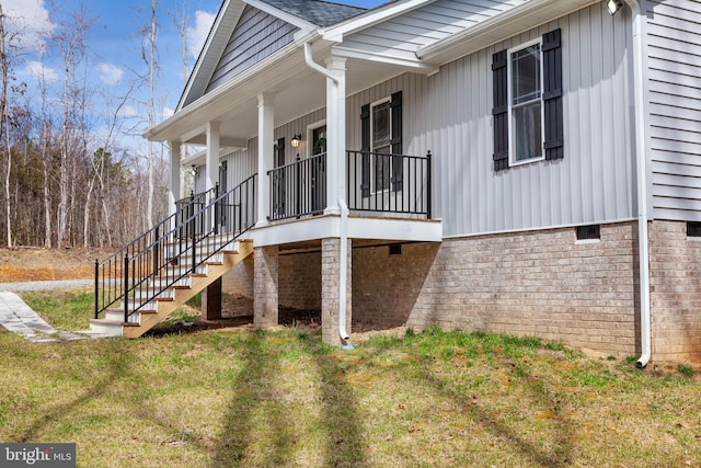 view of home's exterior with crawl space, a lawn, a porch, and stairway