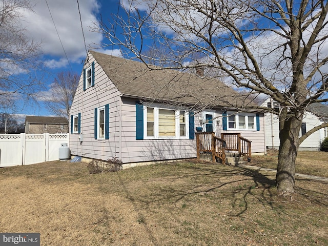 view of front of home featuring a shingled roof, a front yard, and fence