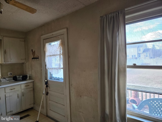 entryway with visible vents, light floors, a textured ceiling, and ceiling fan