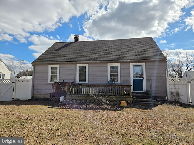 rear view of house featuring entry steps, a gate, a fenced backyard, a shingled roof, and a chimney