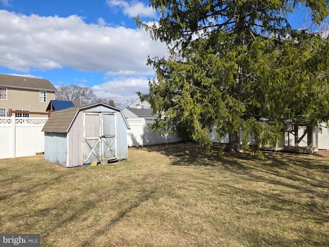 view of yard with an outdoor structure, a fenced backyard, and a shed