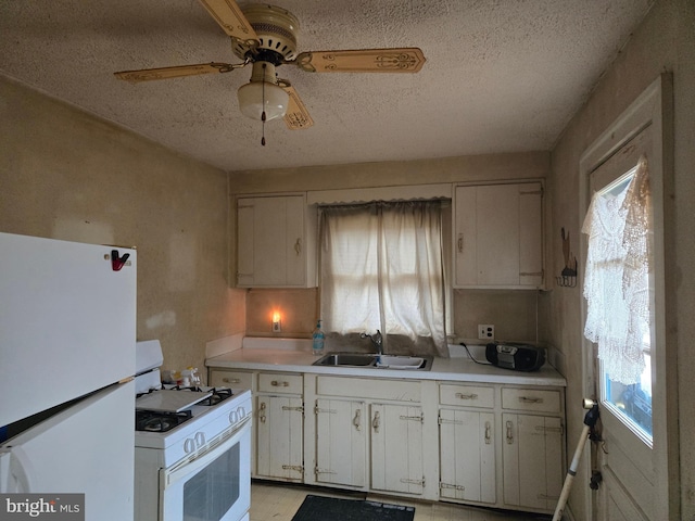 kitchen with white appliances, white cabinets, light countertops, and a sink