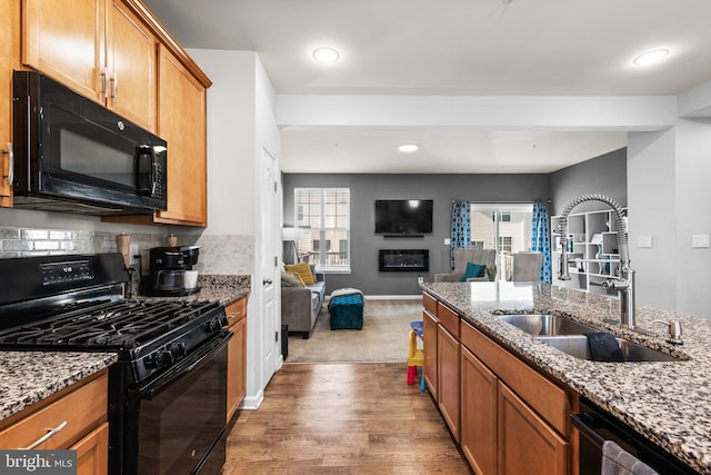 kitchen featuring open floor plan, plenty of natural light, black appliances, and a sink