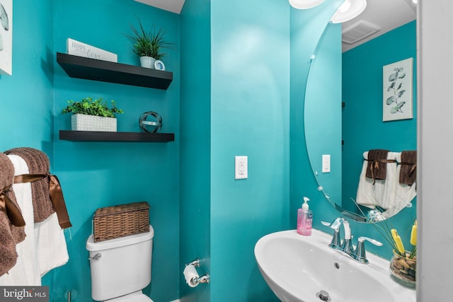 half bath with a sink, visible vents, and toilet