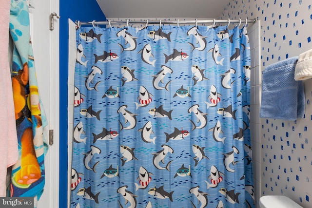 bathroom featuring wallpapered walls, a shower with shower curtain, and toilet