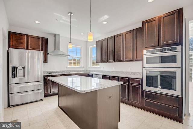 kitchen featuring dark brown cabinetry, stainless steel appliances, wall chimney exhaust hood, and a kitchen island