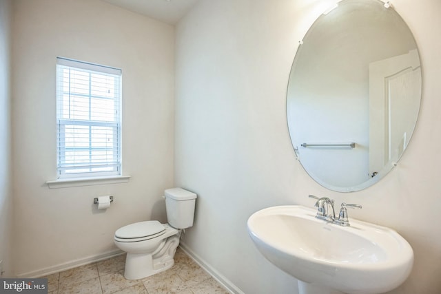 half bath with toilet, a sink, tile patterned floors, and baseboards