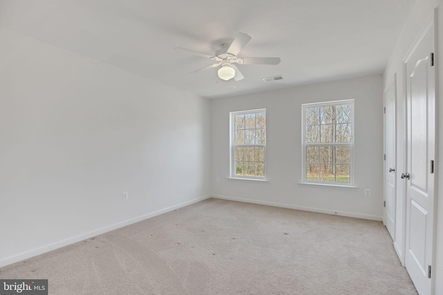 unfurnished bedroom featuring light colored carpet, visible vents, baseboards, and a ceiling fan