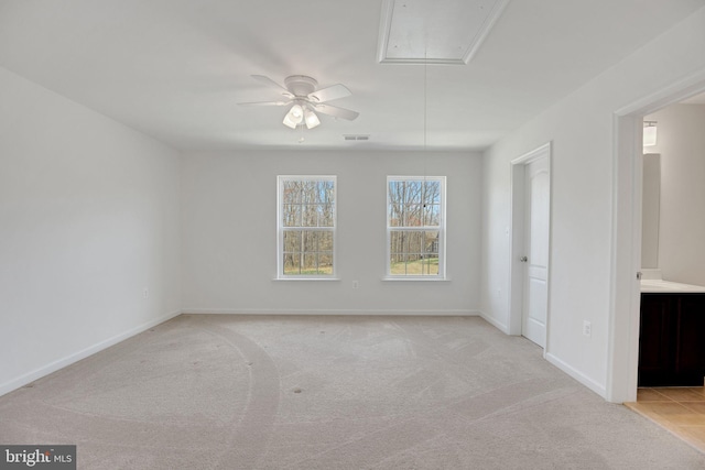 spare room featuring attic access, carpet flooring, baseboards, visible vents, and a ceiling fan