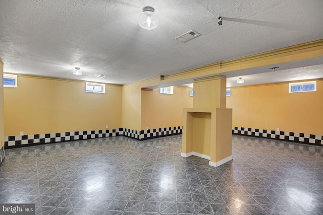 interior space with ornamental molding, a textured ceiling, baseboards, and visible vents