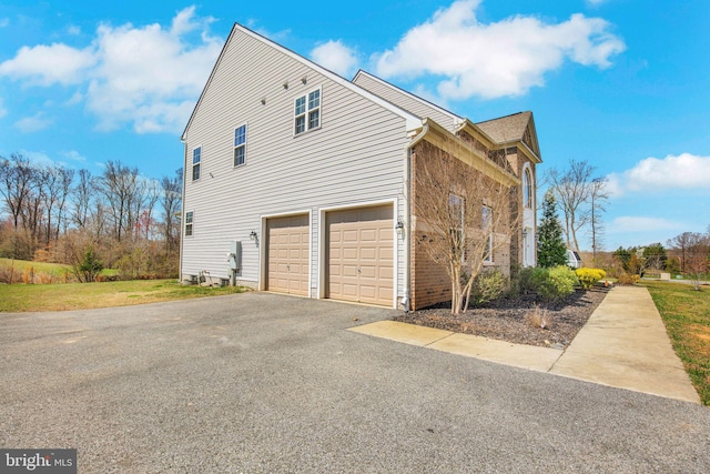 view of side of home featuring driveway and an attached garage