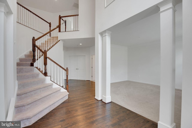 entryway with ornate columns, baseboards, wood finished floors, and crown molding