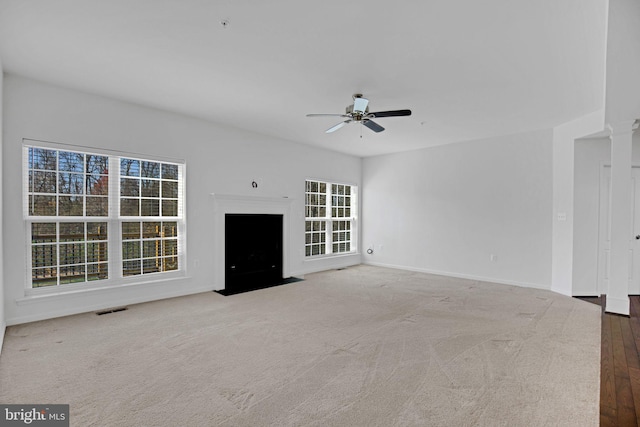 unfurnished living room featuring a ceiling fan, baseboards, visible vents, carpet, and ornate columns