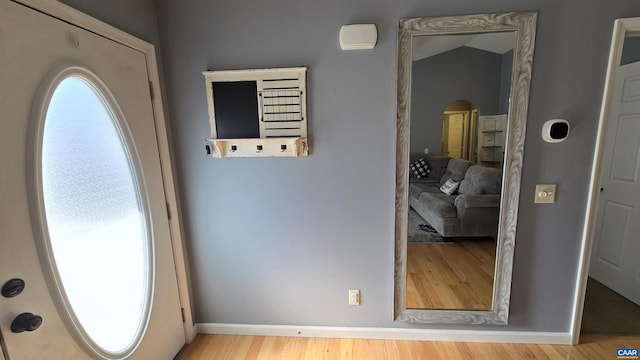 foyer with lofted ceiling, wood finished floors, and baseboards