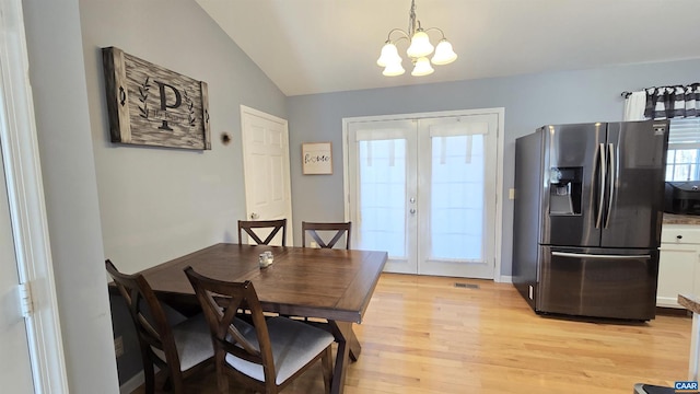 dining room featuring visible vents, a notable chandelier, french doors, light wood-style floors, and vaulted ceiling