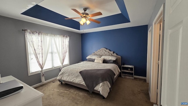 bedroom with a raised ceiling, baseboards, and carpet floors