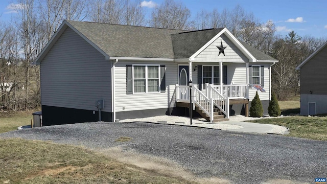 view of front facade featuring covered porch, driveway, and a shingled roof